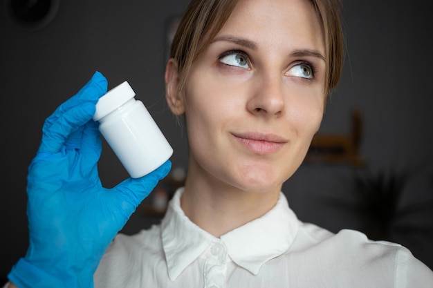 Eine Krankenschwester mit blauen medizinischen Handschuhen hält eine Flasche Pillen
