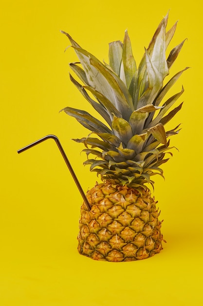 Eine kreative Sommerkomposition mit Ananas und Cocktailtube. Das Konzept eines minimalen Ananasgetränks.