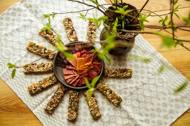 Foto eine kreisförmige zusammensetzung auf dem tisch mit hausgemachten fruchtlederstücken in der schüssel und müsli-riegeln