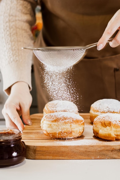 Eine Küchenköchin bereitet in ihrer Bäckerei frische Donuts vor und kocht traditionelle jüdische Hanukkah-Sufganiyot