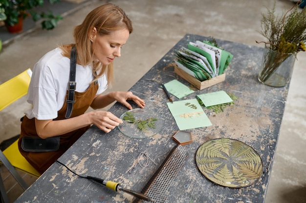 Eine Künstlerin, die kreative Blumenkompositionen am Handwerksarbeitsplatz macht