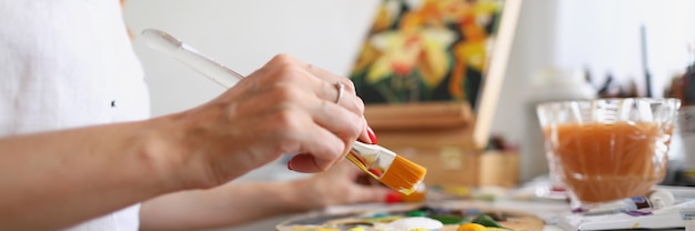 Eine Künstlerin sitzt an einem Tisch und mischt Farbe auf einer Palette mit einem Pinselhobby für einen Jungen