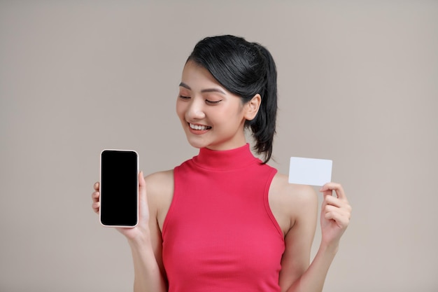 Eine lächelnde Frau bezahlt mit einer Plastikkreditkarte über eine Smartphone-App