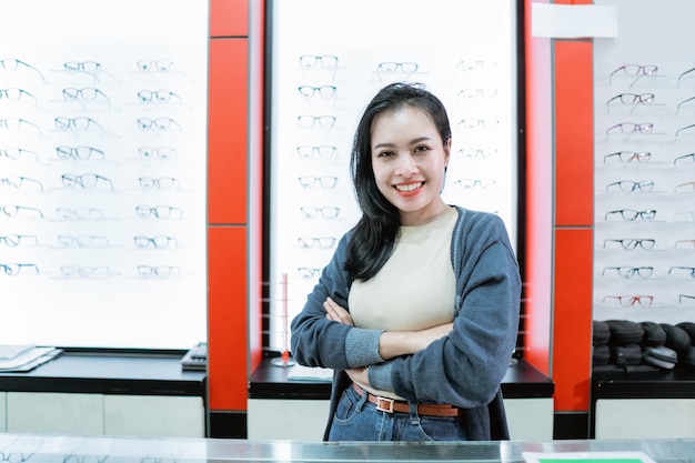Eine lächelnde Frau ist in einer Augenklinik mit einer Brillenfensterwand