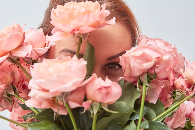Eine lächelnde Frau versteckt ihr Gesicht hinter einem Strauß duftender rosa Rosen. Valentinstag. Frauentag. Nahaufnahme,