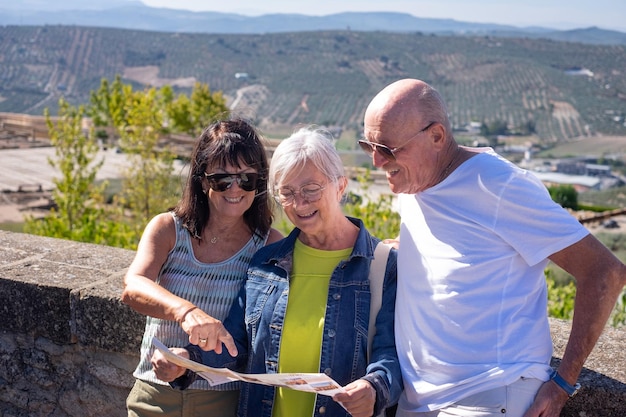 Eine lächelnde Gruppe erwachsener Senioren besucht ein historisches Schloss in Andalusien, Spanien, und schaut auf die Karte