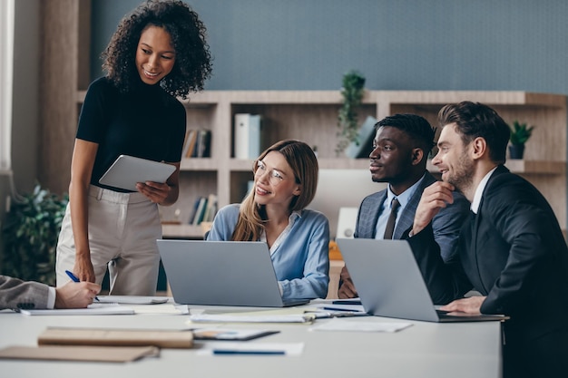 Eine lächelnde Gruppe von Geschäftsleuten diskutiert während eines Teamtreffens am Schreibtisch gemeinsam über die Strategie