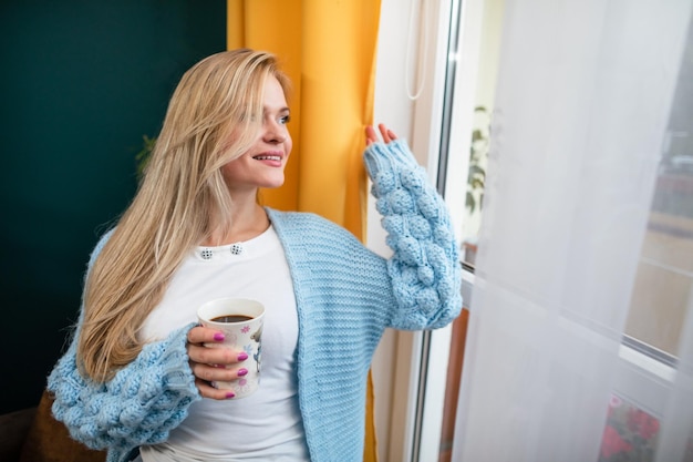 Eine lächelnde junge Frau schaut durch das Fenster nach draußen