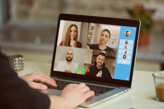 Eine Laptop-Bildschirmansicht über die Schulter einer Frau. Eine Geschäftsfrau bespricht mit ihren Kollegen eine Erklärung in einem Online-Briefing