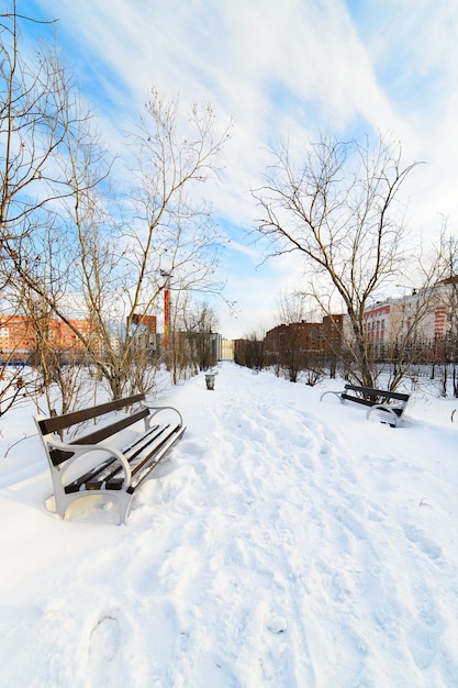 Eine leere Bank im schneebedeckten Stadtpark. Winter.