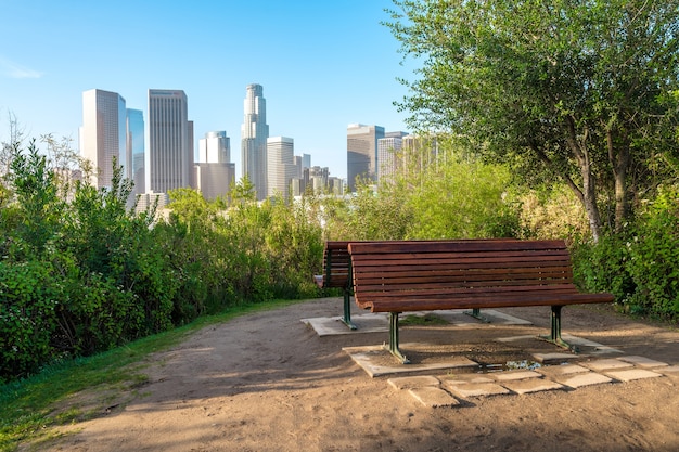 Eine leere Bank in einem Park in Los Angeles mit Blick auf die Wolkenkratzer der Innenstadt