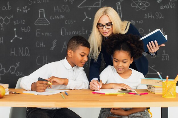 Eine Lehrerin hilft Schulkindern, Probleme in der Schule zu lösen Internationale Mannschaft Zurück in die Schule