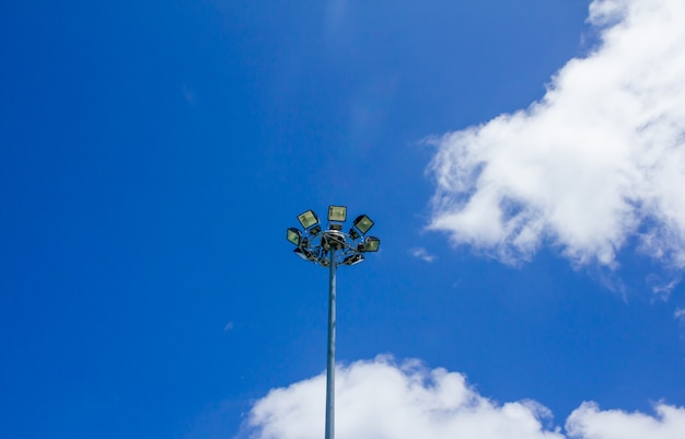 Eine Lichtlampe auf einer Stange gegen den blauen Himmel, Sportlicht mit blauem Himmelwolkenhintergrund