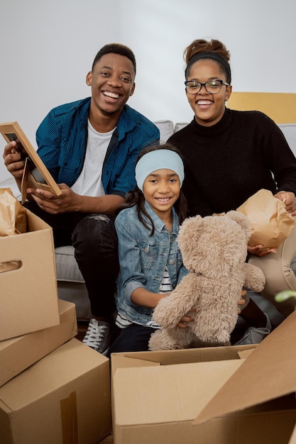 Eine liebevolle Familie sitzt auf der Couch im Wohnzimmer und packt eine Vielzahl von Kartons aus, die um sie herumstehen