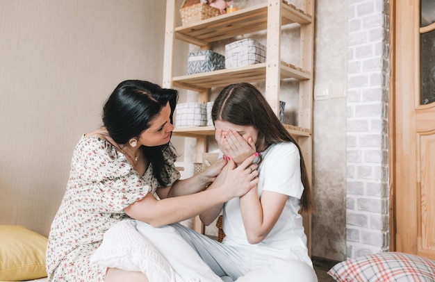 Eine liebevolle Mutter und Tochter mittleren Alters sitzen auf dem Boden, ein besorgter Elternteil beruhigt ein Kind mit gebrochenem Herzen, erster Liebe, dem Konzept der Fürsorge und Unterstützung