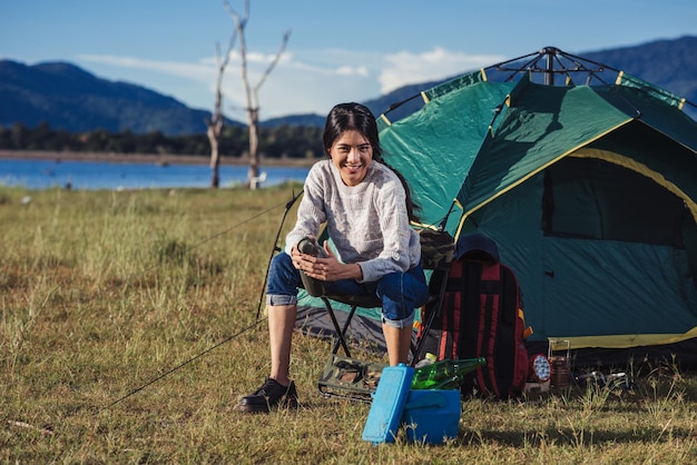 Eine Lifestyle-Frau, die im Natursommer im Naturwald auf einem Campinglager sitzt