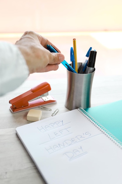 Eine linke Hand, die mit einem Stift in einem Notizbuch zum internationalen Tag der Linkshänder schreibt.