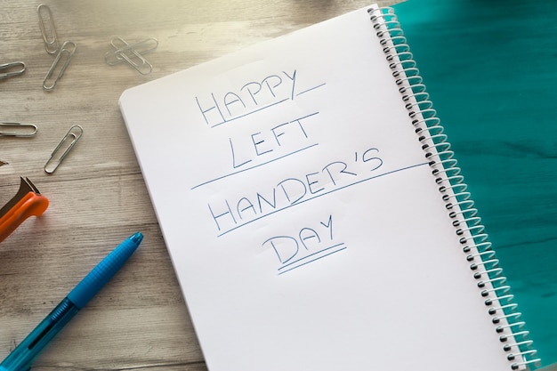 Eine linke Hand, die mit einem Stift in einem Notizbuch zum internationalen Tag der Linkshänder schreibt.