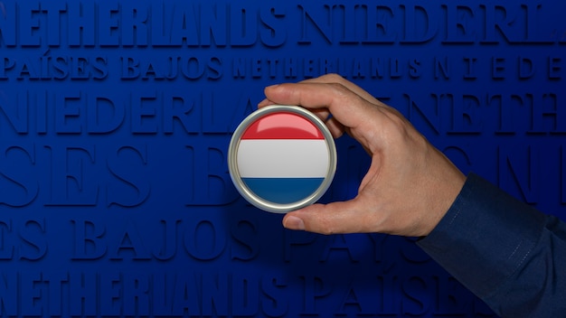 Eine männliche Hand, die ein Abzeichen mit der Nationalflagge der Niederlande auf dunkelblauem Hintergrund hält