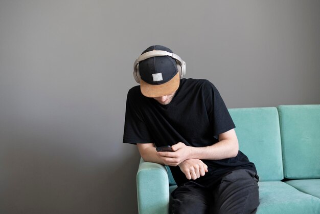 Eine männliche Person, die auf der Couch sitzt und zu Hause Musik über Kopfhörer hört