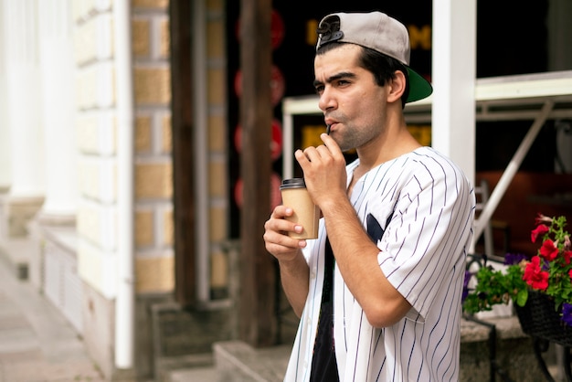 Eine männliche Person, die auf der Straße der Stadt spaziert und den Espresso, Kaffee zum Mitnehmen trinkt?