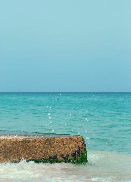 Eine Meereslandschaft mit türkisfarbenem Wasser Ein großer Felsen im Meer, der von den Wellen umspült wird