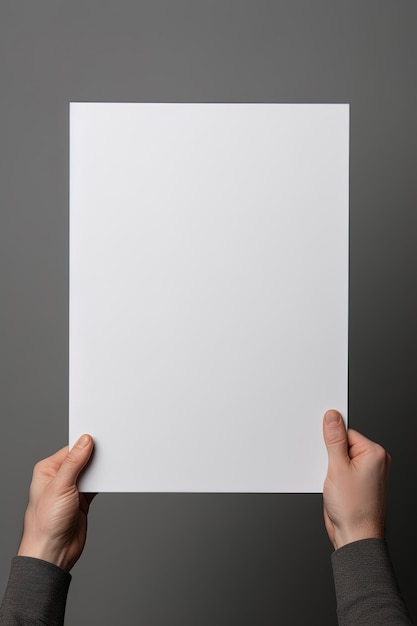Eine menschliche Hand hält ein leeres Blatt weißes Papier oder eine Karte, die auf grauem Hintergrund isoliert ist