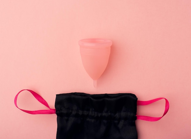 Eine Menstruationstasse und ein Beutel auf rosafarbenem Hintergrund Null-Abfall-Konzept