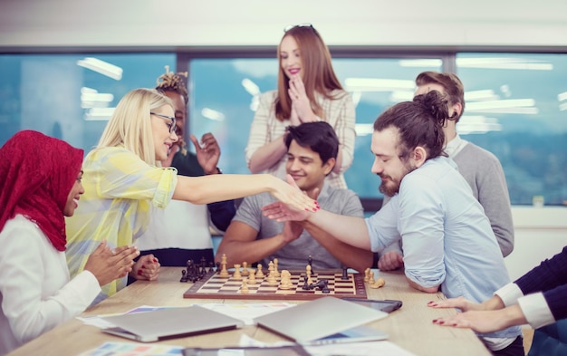 Eine multiethnische Gruppe von Geschäftsleuten, die Schach spielen, während sie eine Pause im modernen Startup-Büro machen