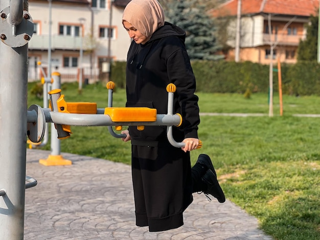 Eine muslimische Frau mit Hijab trainiert frühmorgens Eine muslimische Frau in Sportkleidung dehnt sich im Freien