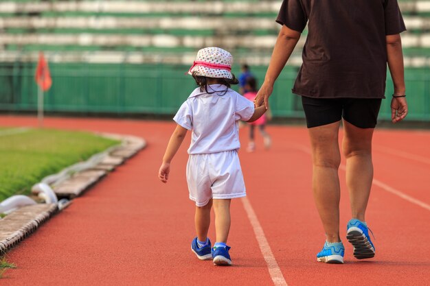 Eine Mutter, die die Hand ihrer Tochter hält und in Laufbahn geht