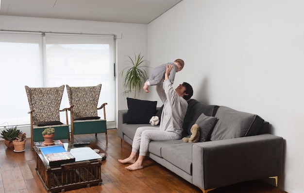 Eine Mutter, die zu Hause mit dem Baby auf dem Sofa spielt