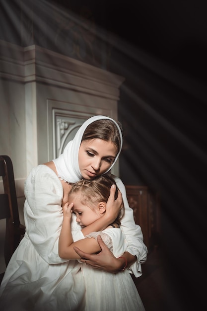 Eine Mutter mit einem kleinen Kind in einem Tempel oder einer Kirche betet neben einer Ikone und Kerzen oder kam zu einem Gottesdienst in der russisch-orthodoxen Kirche zur Taufe eines Babys