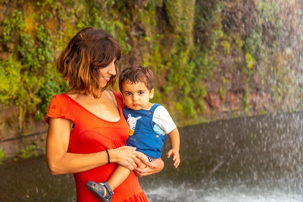 Eine Mutter mit ihrem Sohn in einem roten Kleid am Anjos Wasserfall Madeira hat Spaß