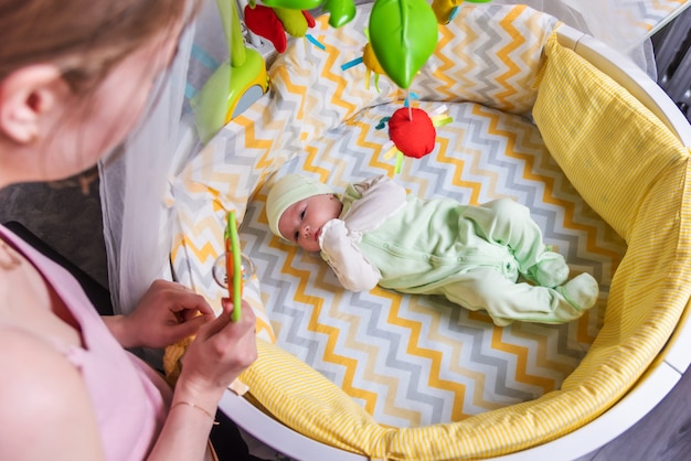 Eine Mutter sieht ihr neugeborenes Baby an, das in einem Kinderbett liegt