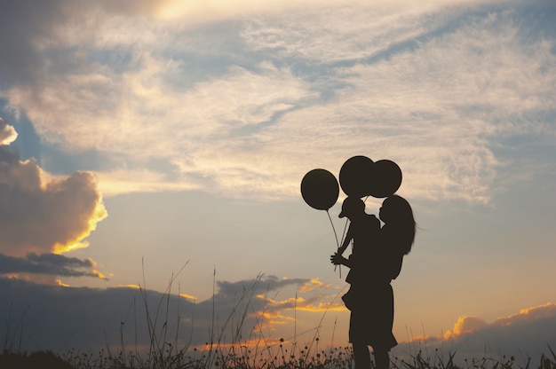 Eine Mutter und ein Sohn, die draußen an Sonnenuntergangschattenbild spielen