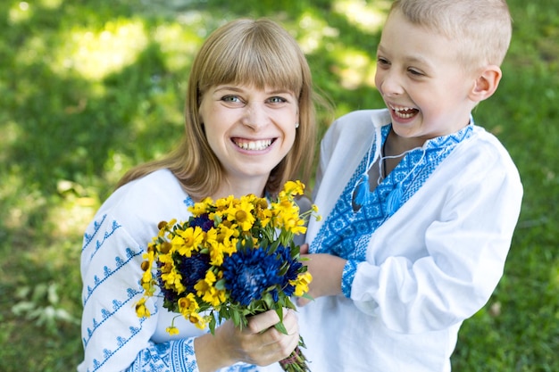 Eine Mutter und ein Sohn halten Blumen in der Hand und lächeln