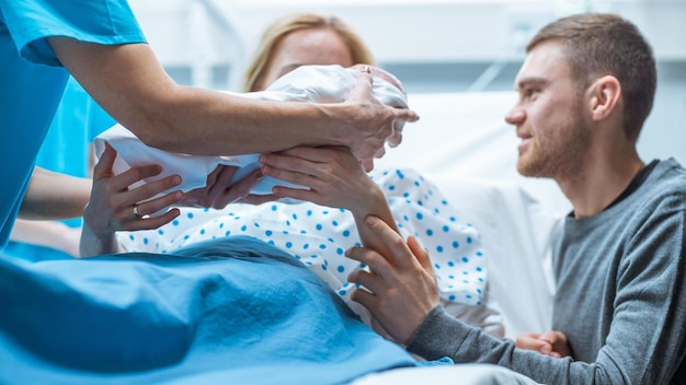 Eine Mutter und ein Vater halten ein neugeborenes Baby in einem Krankenhausbett