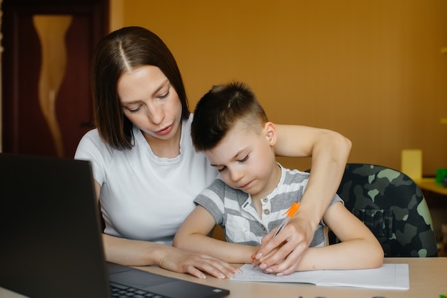 Eine Mutter und ihr Kind machen Fernunterricht zu Hause vor dem Computer