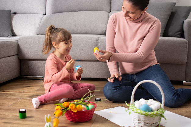 Eine Mutter und ihre Tochter malen Ostereier zu Hause.