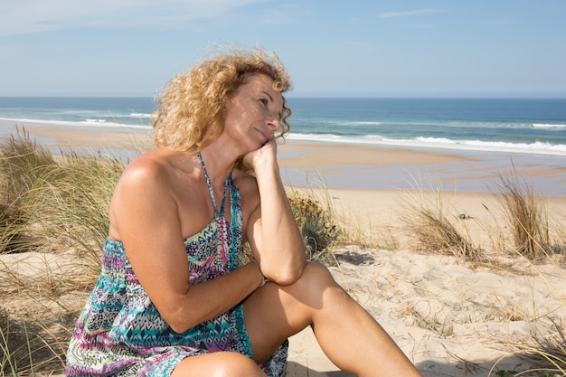 Eine nachdenkliche Frau am Wasser im Sand