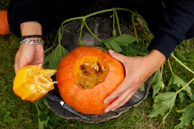 Eine Nahaufnahme der Hand eines Mannes schneidet einen Deckel von einem Kürbis, während er einen Jack Olantern zubereitet. Halloween. Dekoration für Party.