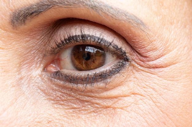 Eine Nahaufnahme des braunen Auges einer älteren Dame mit Falten und Krähenfüßen