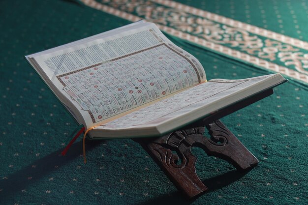 Foto eine nahaufnahme des heiligen buches alquran auf einem grünen gebetsteppich islamisches foto-konzept