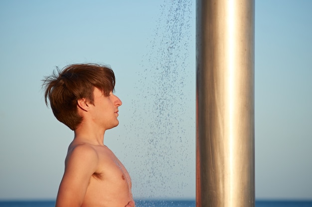 Eine Nahaufnahme des jungen Mannes, der am Strand duscht.