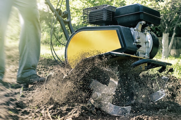 Eine Nahaufnahme des Motorgrubbers während des Pflugprozesses im Frühjahr Gartenarbeitskonzept