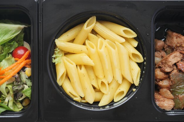 Foto eine nahaufnahme einer schüssel mit nudeln neben einer schüssel mit salat und einer schüsel mit fleisch