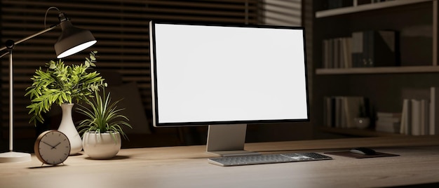 Eine Nahaufnahme eines Computers mit einem weißen Bildschirmmockup auf einem Holztisch in einem Raum bei Nacht