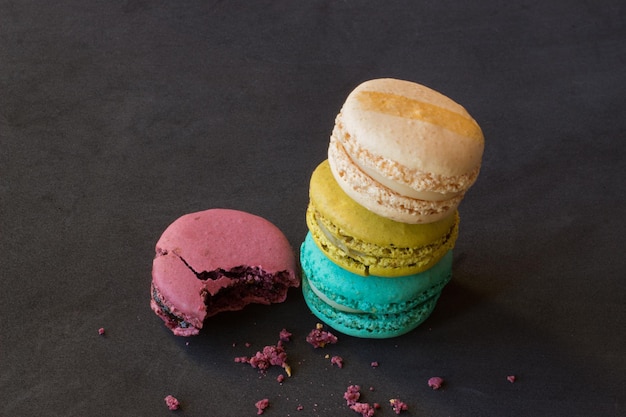 Eine Nahaufnahme eines Stapels bunter Macarons und Krümel auf einer schwarzen Oberfläche