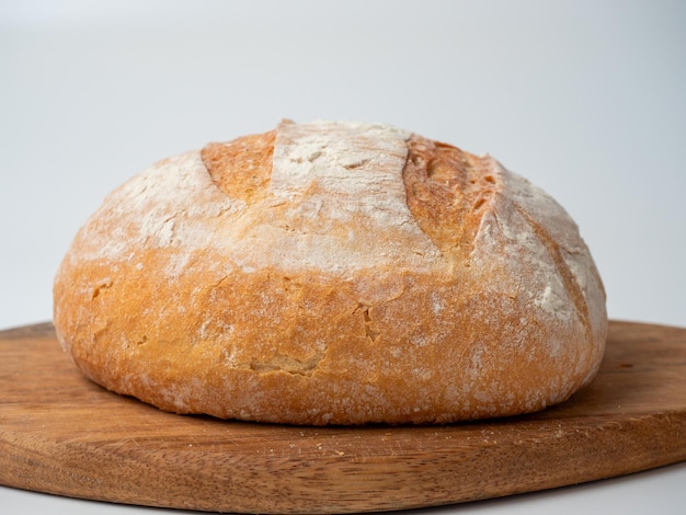 Eine Nahaufnahme von frisch gebackenem Weizenbrot mit knuspriger Kruste liegt auf einem Holztablett Bäckereikonzept mit Seitenansicht